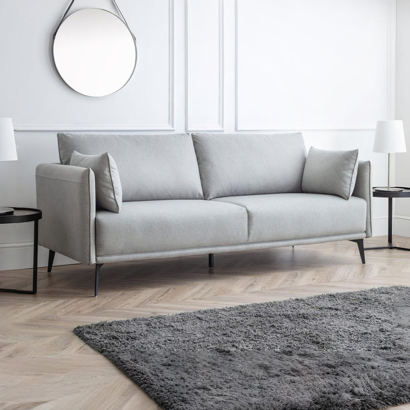 Gray sofa in a modern living room with a rug and side tables.
