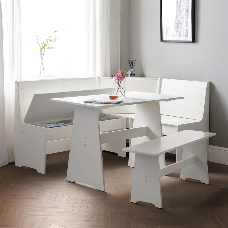 White dining set with table and benches in a room with light gray walls and wooden flooring.
