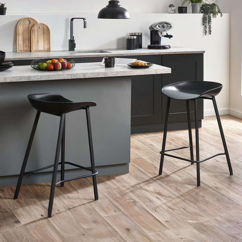 Modern kitchen with gray island, black bar stools, and wooden flooring.