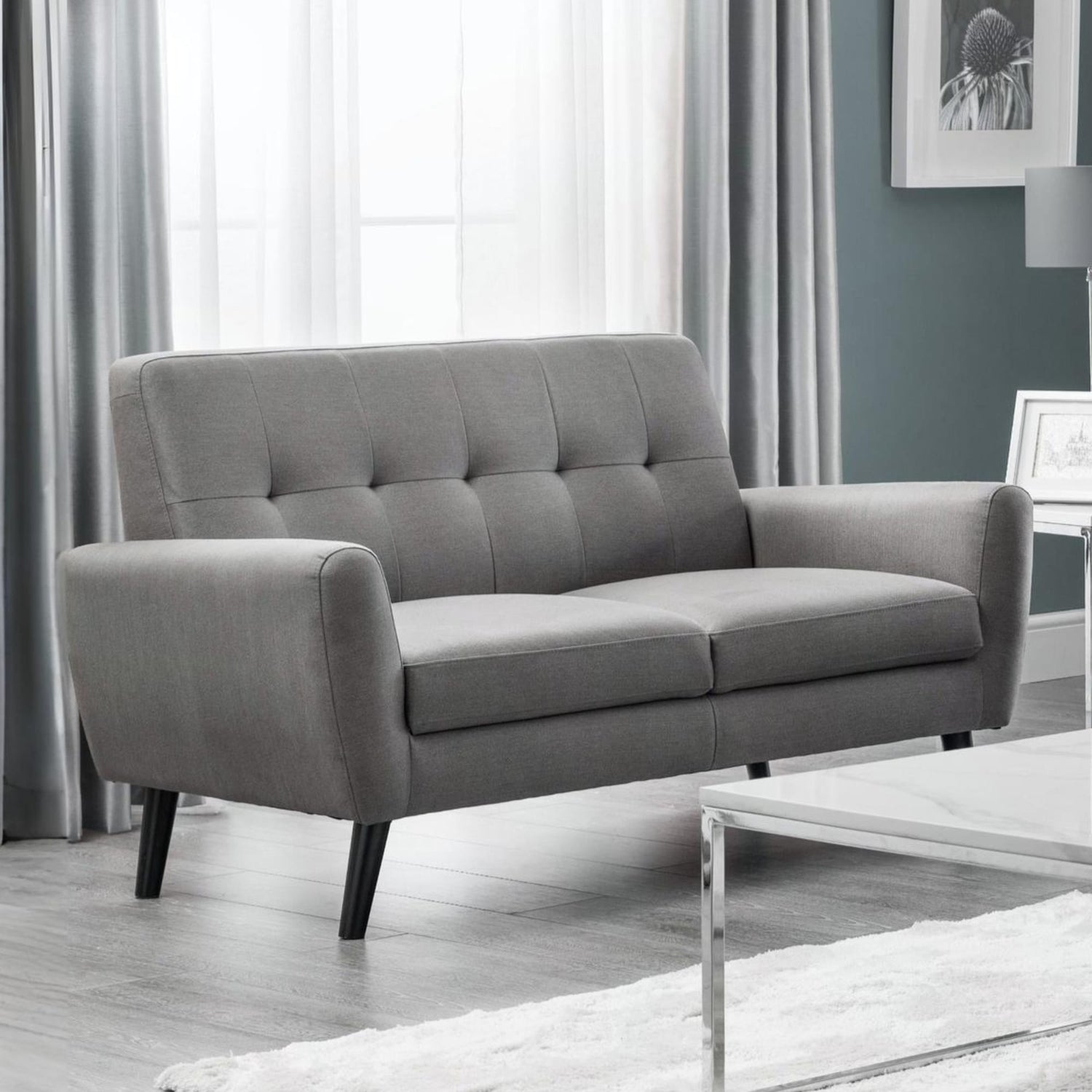 Gray sofa in a living room setting with curtains and a coffee table.