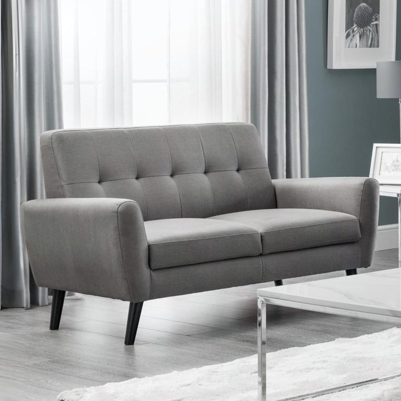 Gray sofa in a living room setting with curtains and a coffee table.