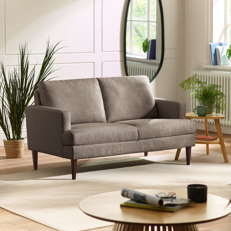 Gray sofa in a living room with a round coffee table and plants.