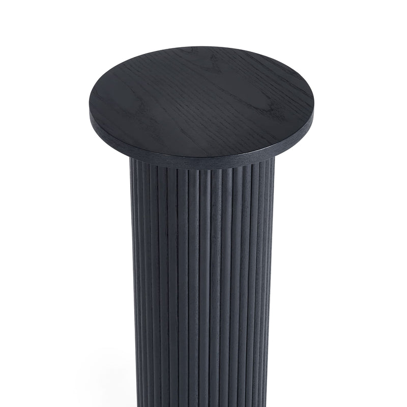 Black cylindrical stool with a ribbed design on a white background