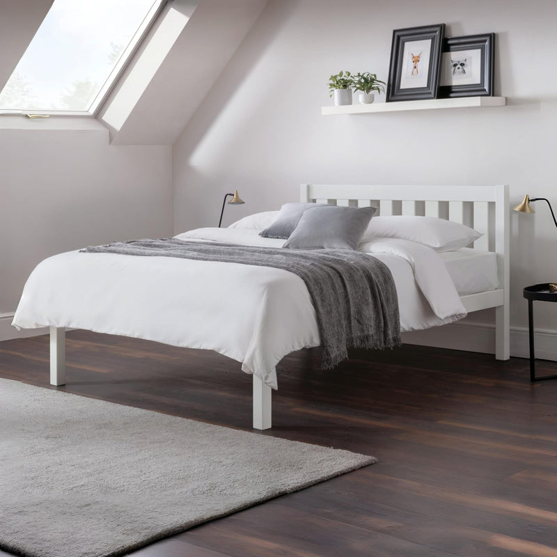 Modern bedroom with a white bed, gray blanket, and decorative elements.
