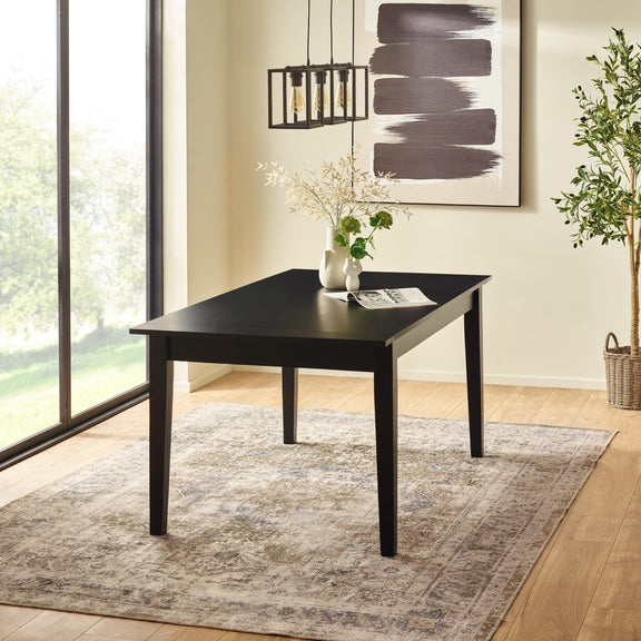 Black dining table in a room with large windows, rug, and decorative elements.