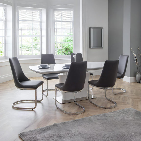Modern dining room with a white table and black chairs in a well-lit room.