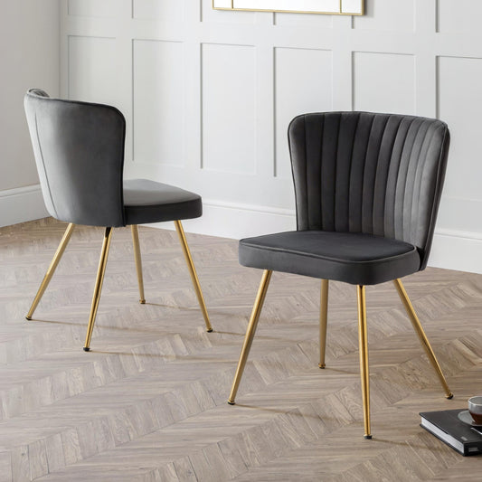 Two gray chairs with gold legs on a wooden floor.