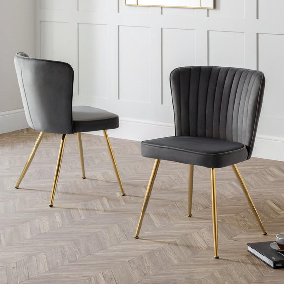 Two gray chairs with gold legs on a wooden floor.