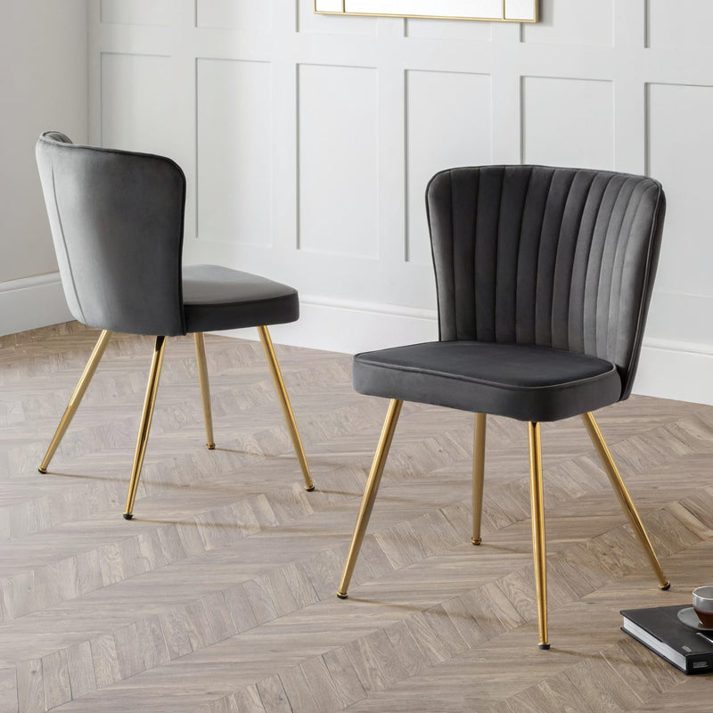 Two gray chairs with gold legs on a wooden floor.