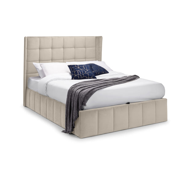 Beige upholstered bed with white bedding and a dark blue blanket on a white background