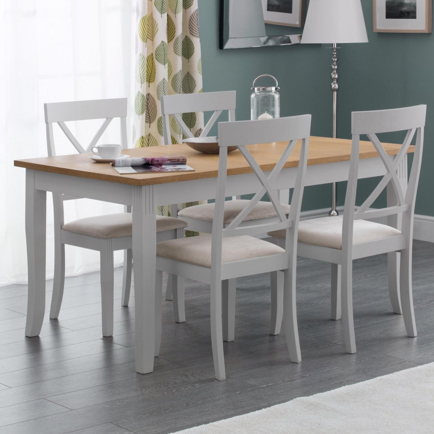 Dining room with a wooden table and white chairs against a green wall.