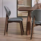 Dining table with two gray upholstered chairs on a wooden floor.