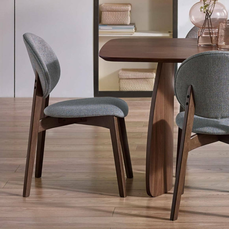 Dining table with two gray upholstered chairs on a wooden floor.