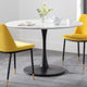 Round dining table with black pedestal base and two yellow chairs in a room.