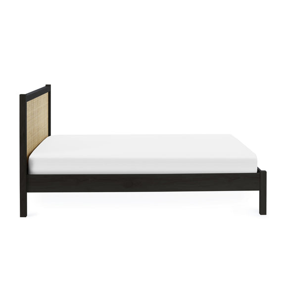 Bed with black frame and woven headboard on a white background