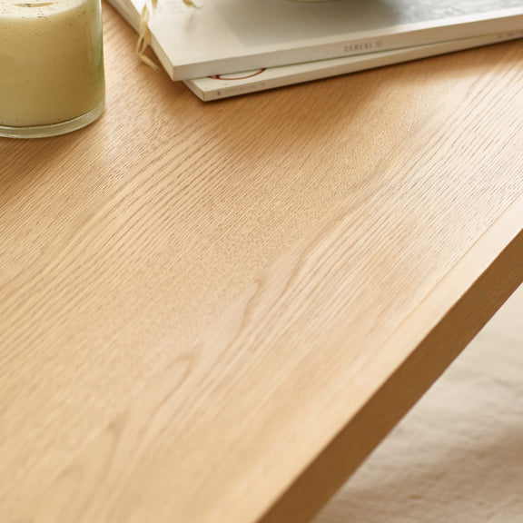 Close-up of a wooden desk surface with a glass of green liquid on it.