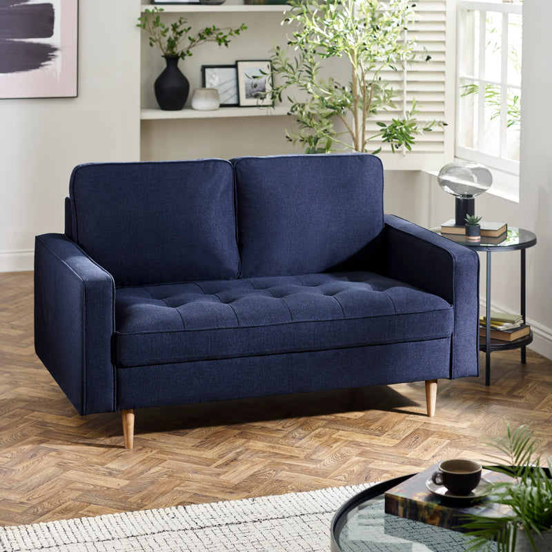 Navy blue sofa in a living room with wooden floor and decorative items.