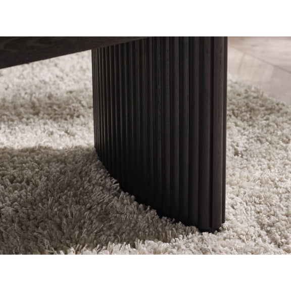 Dark wooden leg of a piece of furniture on a textured beige carpet