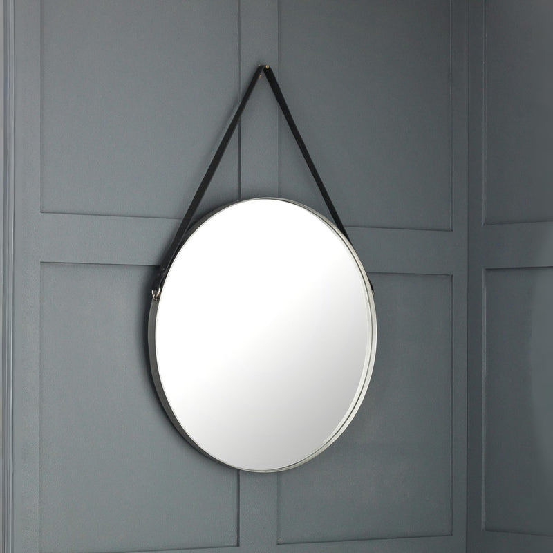 Round mirror with black strap hanging on a gray paneled wall