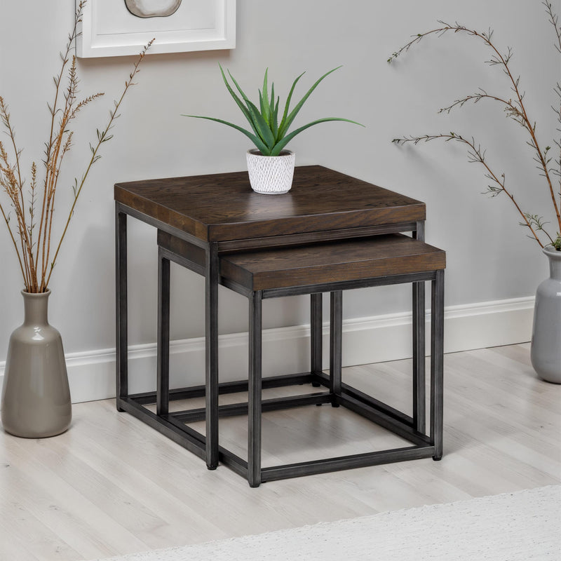 Set of two wooden nesting tables with a plant on top in a room setting.