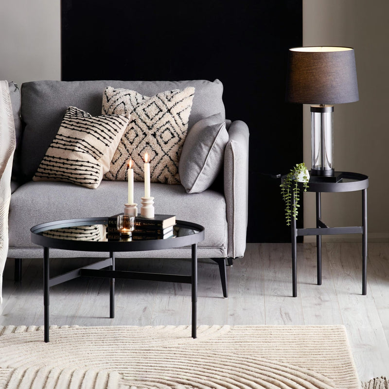 Modern living room with gray sofa, decorative pillows, and side table.