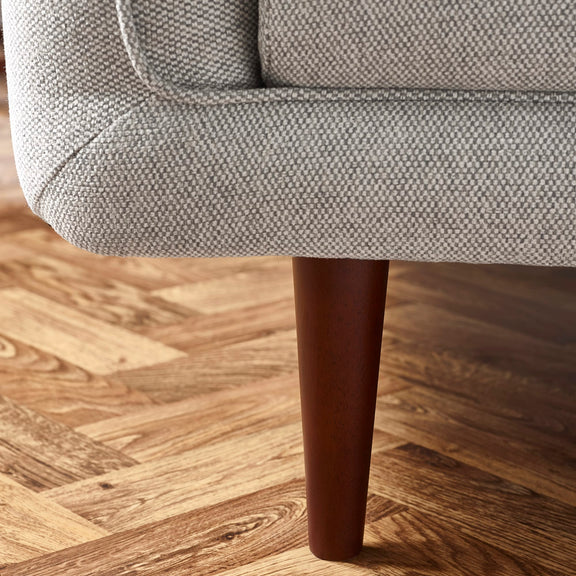 Gray textured armchair with wooden leg on a wooden floor