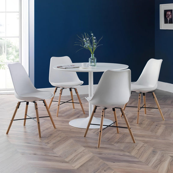 Modern dining set with white chairs and a round table against a blue wall.