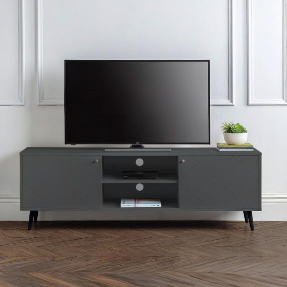 Gray TV stand with a television and decorative items in a room with white walls and wooden flooring.