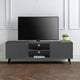 Gray TV stand with a television and decorative items in a room with white walls and wooden flooring.