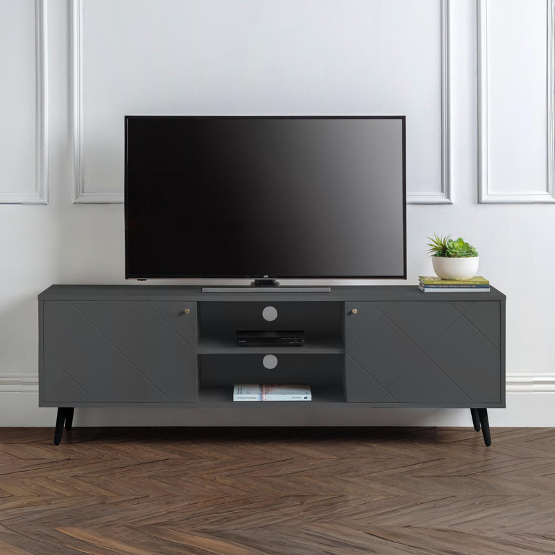 Gray TV stand with a television and decorative items in a room with white walls and wooden flooring.