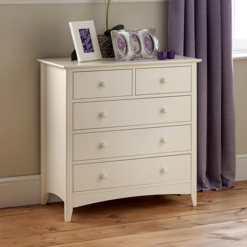 Beige chest of drawers with decorative items against a neutral wall.