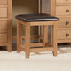 Wooden stool with a black leather seat in front of wooden furniture.
