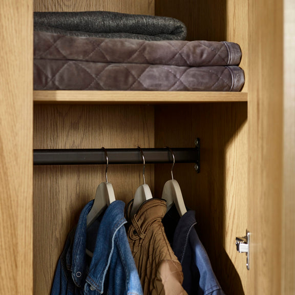 Closet with folded clothes on a shelf and hanging garments below.