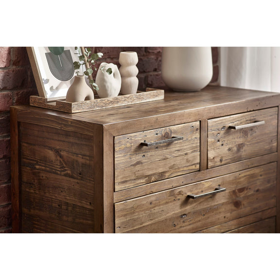 Wooden dresser with decorative items on top against a brick wall.