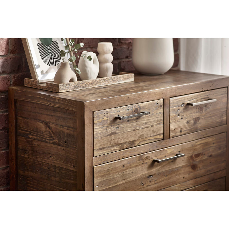 Wooden dresser with decorative items on top against a brick wall.