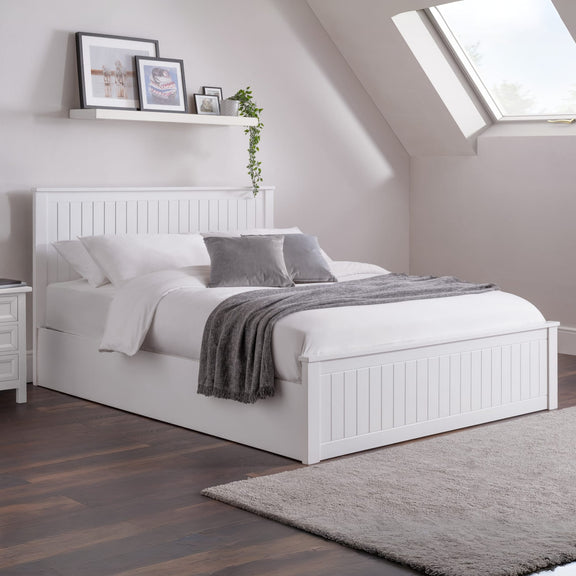 White bed in a bedroom with wooden floor and skylight