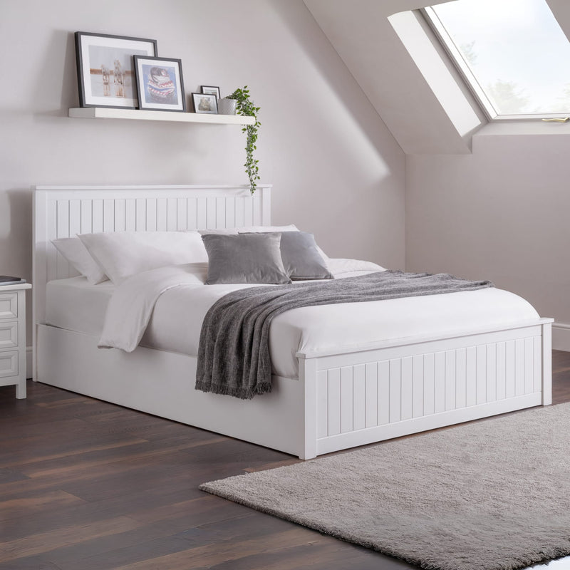 White bed in a bedroom with wooden floor and skylight
