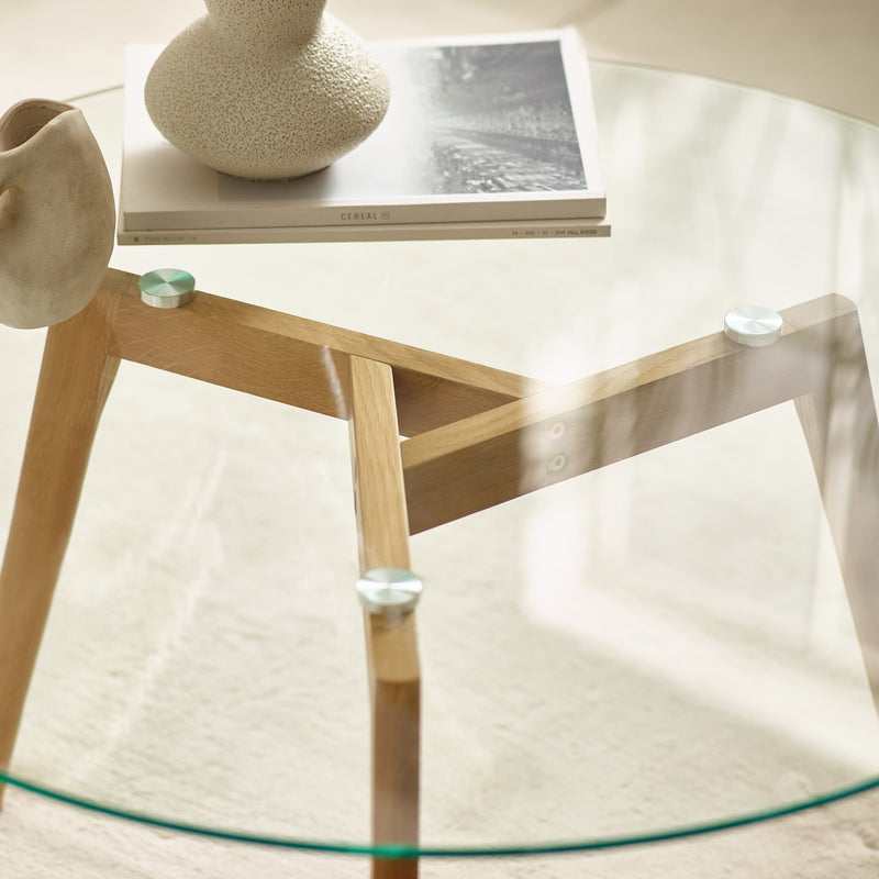 Glass table with wooden legs on a light background