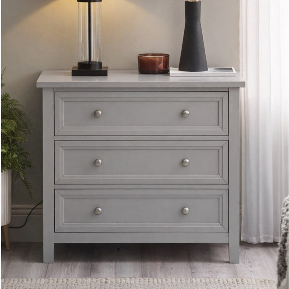 Gray dresser with three drawers in a room setting.