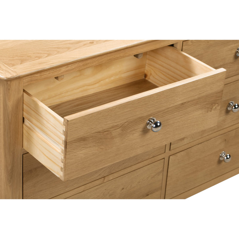 Wooden dresser with an open drawer and metal handles on a white background