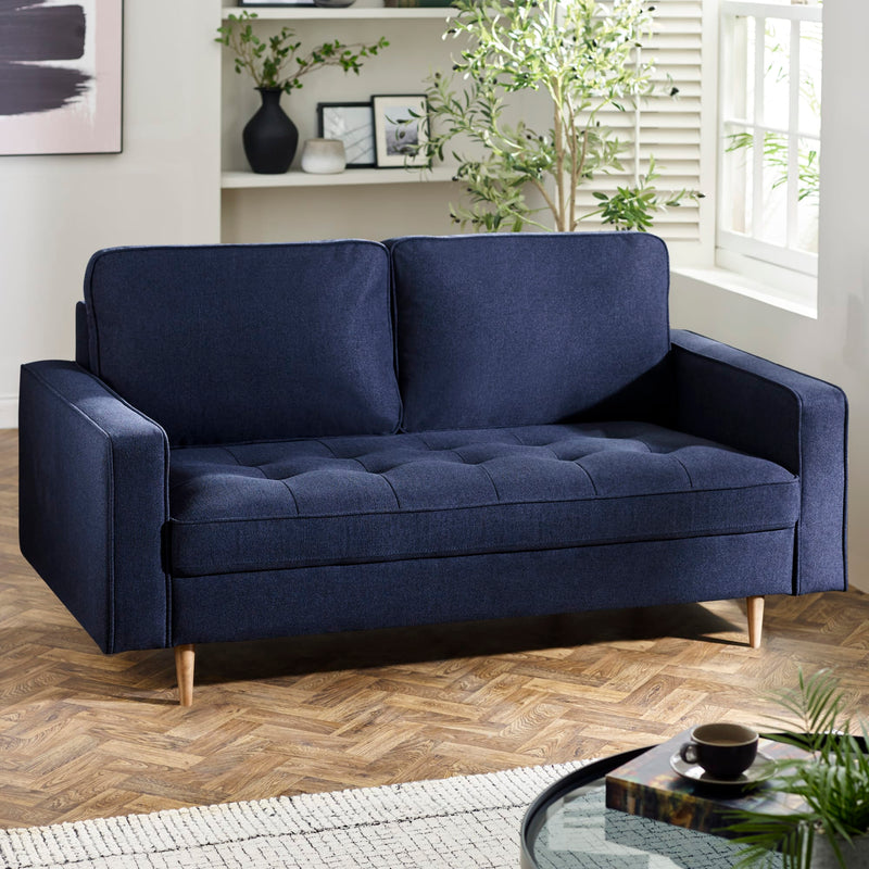 Blue sofa in a living room with a coffee table and plants.