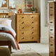 Wooden dresser in a bedroom with a bed and decor