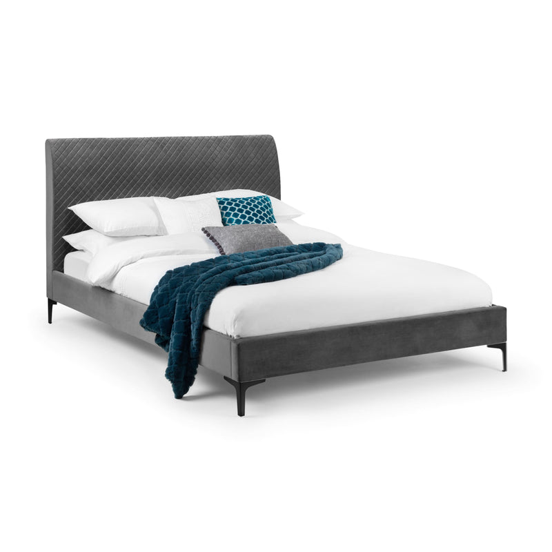 Gray upholstered bed with white bedding and blue blanket on a white background