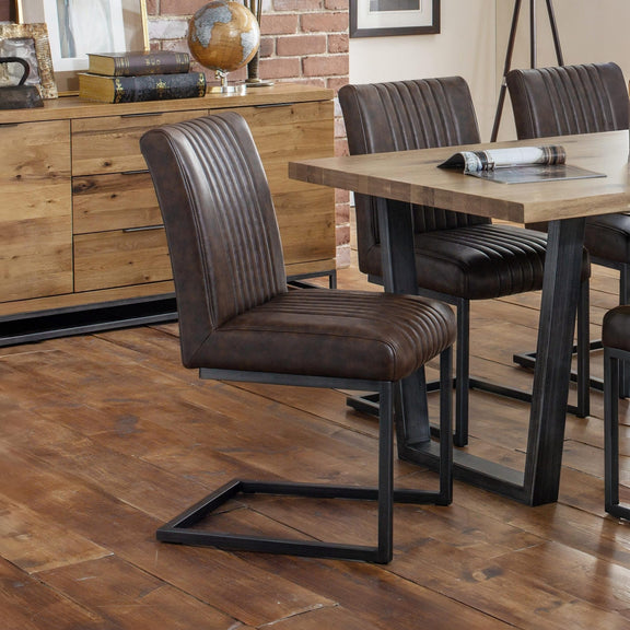 Dining room with wooden table and brown leather chairs on a wooden floor.