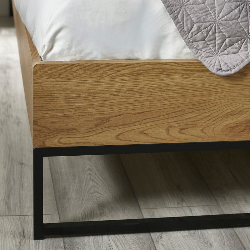 Wooden bed frame with metal legs on a wooden floor
