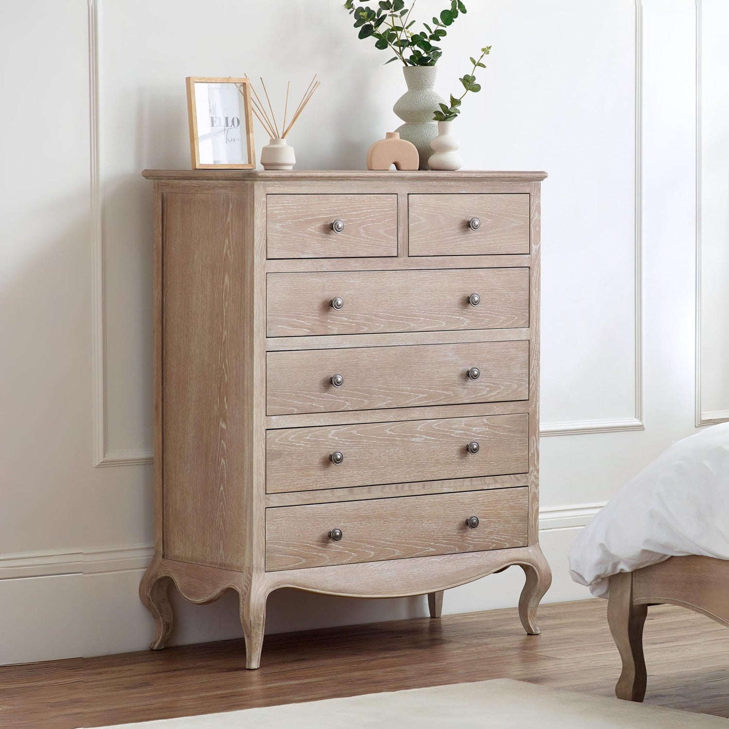 Wooden dresser with five drawers in a bedroom setting