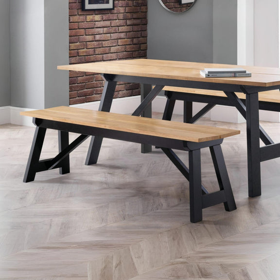 Wooden dining table and benches in a room with a brick wall.
