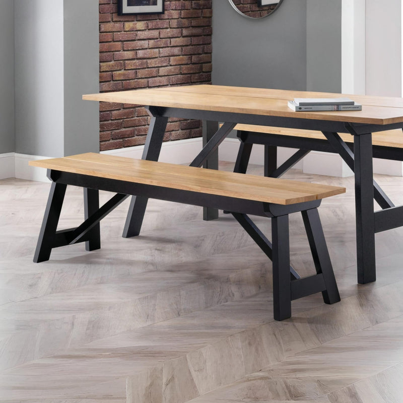 Wooden dining table and benches in a room with a brick wall.
