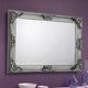 Decorative silver mirror with intricate designs on a purple wall.