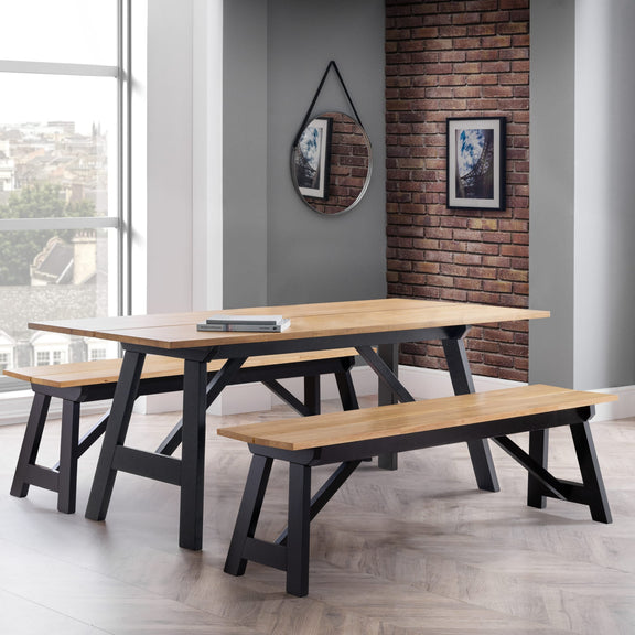 Wooden dining table with benches in a modern room with a brick wall and large window.